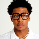 Black Male model wearing Icon Oversized Eyeglasses, Black acetate eyeglasses by AKA SAVRAN, with Orange accents