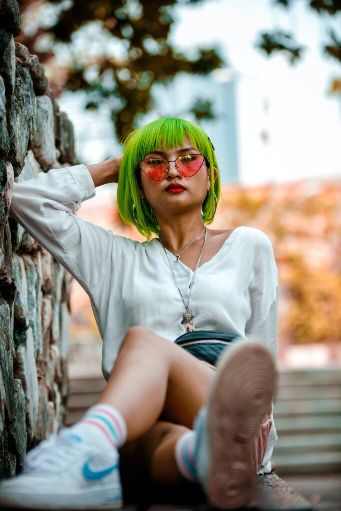 Asian girl with green hair and wearing colourful sunglasses with pink lenses