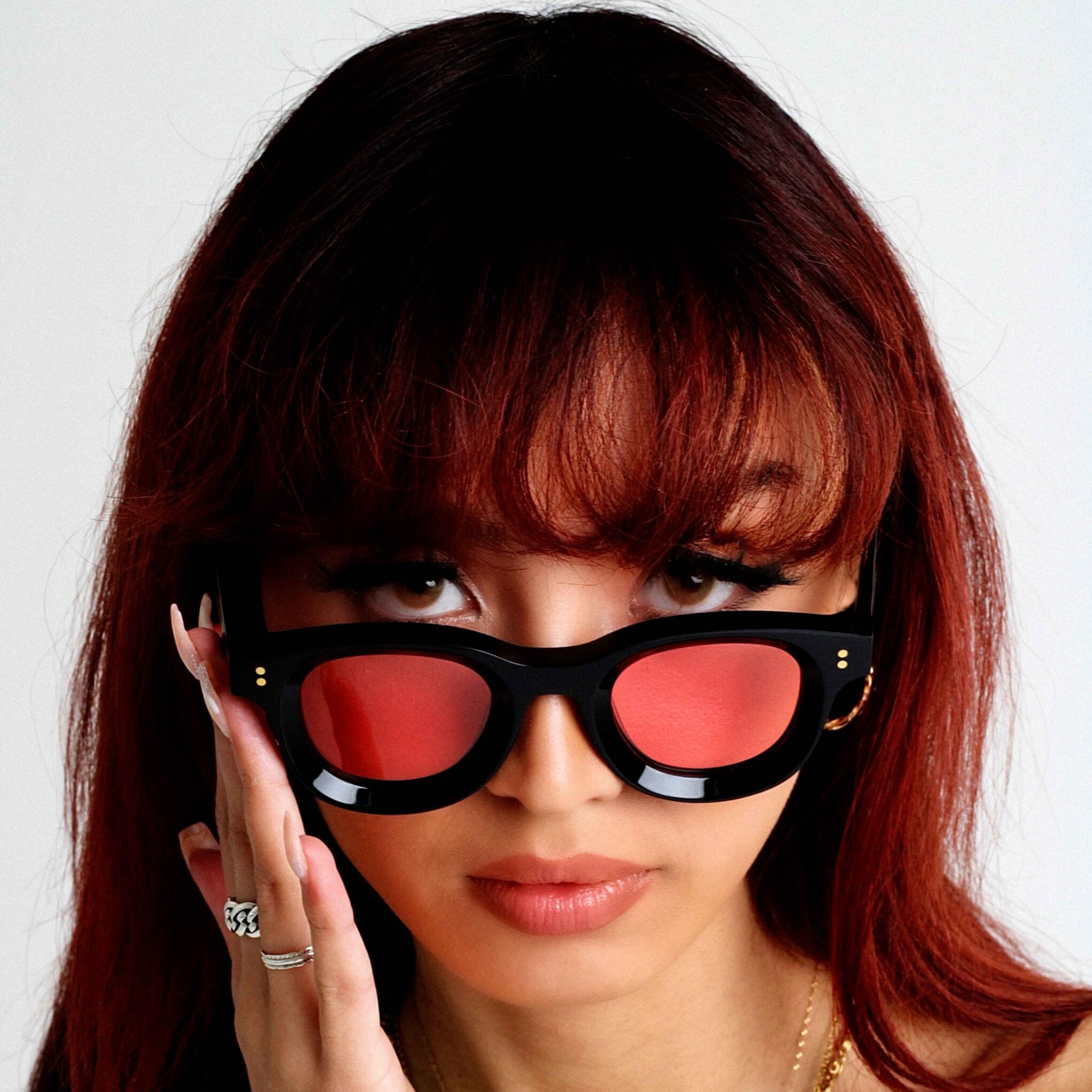 Aziatisch vrouwelijk model draagt KOKO ROUGE, luxe ronde zonnebril uit KOKO SUNGLASSES COLLECTION van AKA SAVRAN