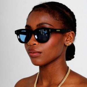 Modelo femenina negra que lleva KOKO BLEU, lujosas gafas de sol redondas de la COLECCIÓN KOKO SUNGLASSES de AKA SAVRAN